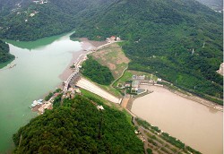 石門水庫、大壩及後池全景。攝影時值馬莎颱風兩星期之後,水庫水色澄清而供應自來水的後池水色仍然混濁。原因是上游帶來的泥沙沉入水庫下層,經由電廠發電後進入後池之結果。目前已在大壩上游增建自來水取水塔,可引取水庫上層清水。 ( 李錫堤攝于2005 年8 月20 日)