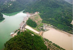 石門水庫、大壩及後池全景。攝影時值馬莎颱風兩星期之後，水庫水色澄清而供應自來水的後池水色仍然混濁。原因是上游帶來的泥沙沉入水庫下層，經由電廠發電後進入後池之結果。目前已在大壩上游增建自來水取水塔，可引取水庫上層清水。 ( 李錫堤攝于2005 年8 月20 日)